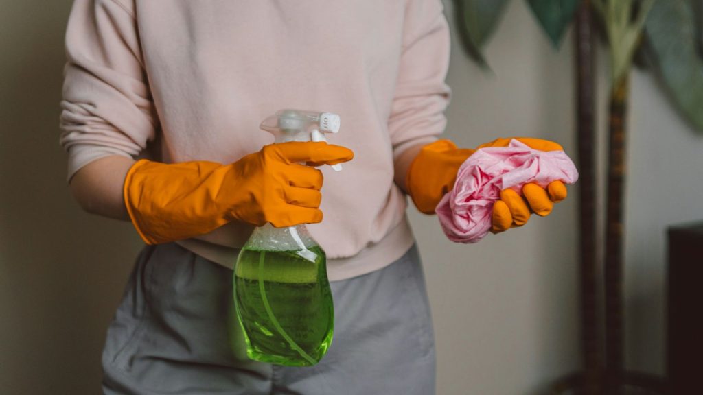 a woman wearing gloves with rug and cleaning product on her hand