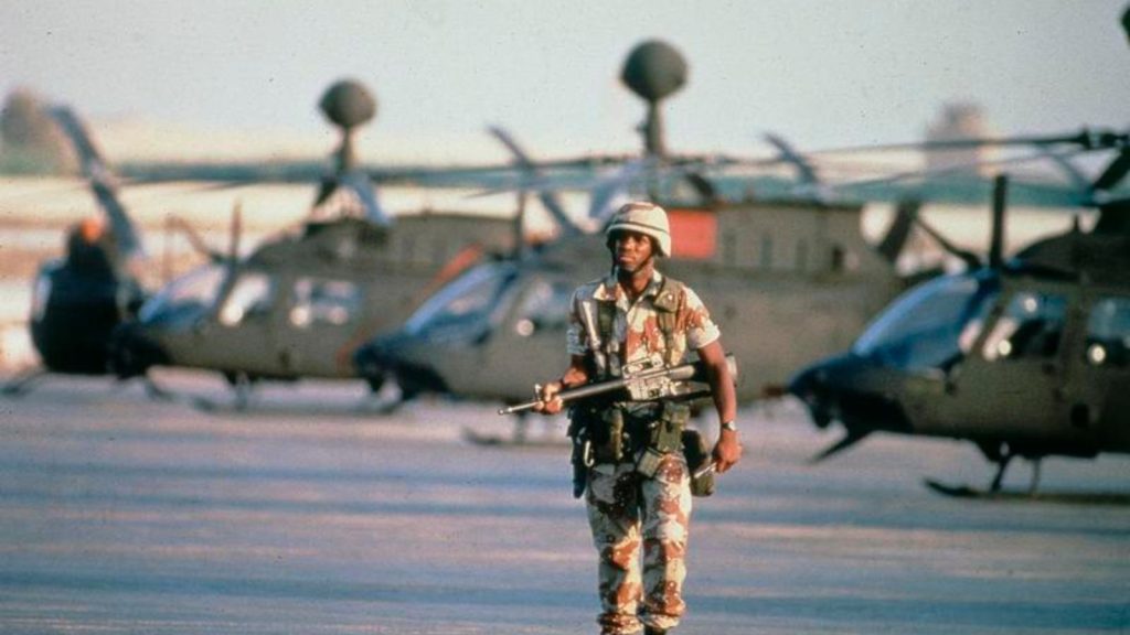 a soldier walking along a line-up of helicopters