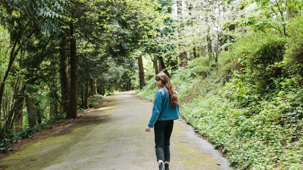 a woman walking on a road with trees