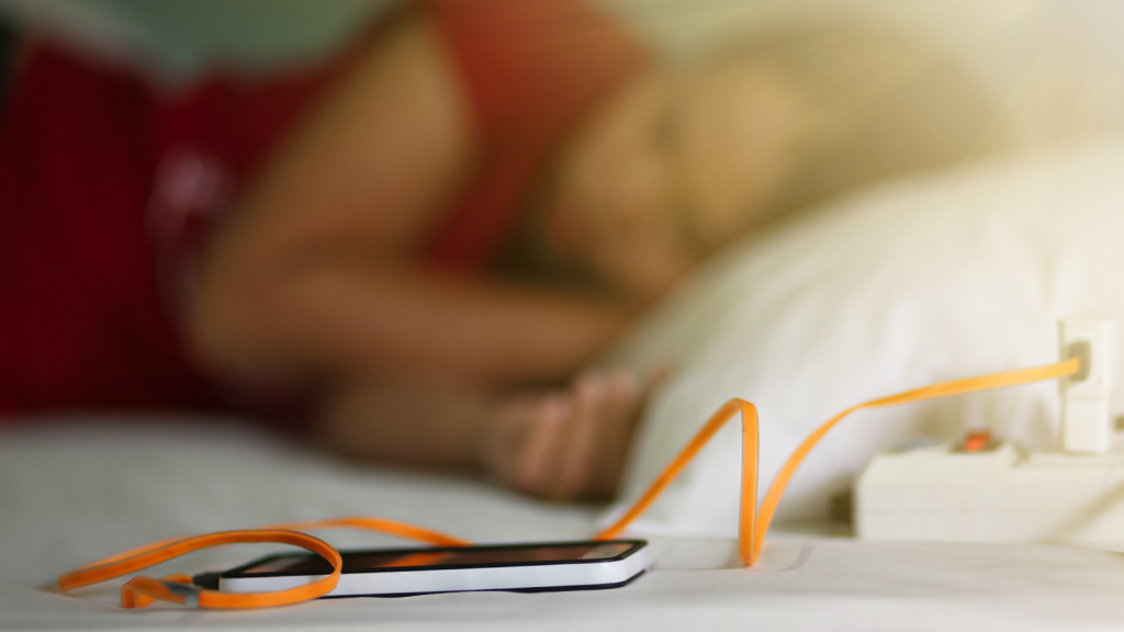 Woman sleeping in bed and holding a mobile phone with battery charging background