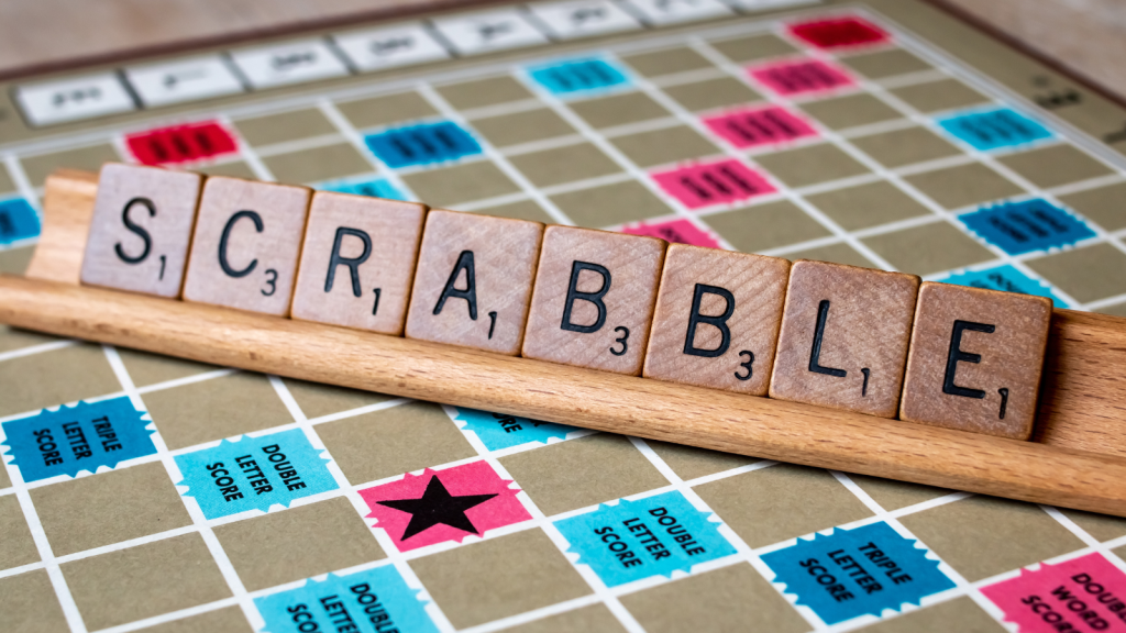 Wooden block letters spell out scrabble on a player rack on the Scrabble game board