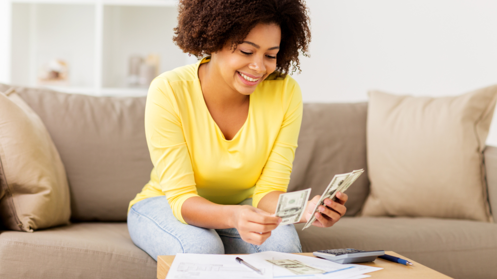 happy african american woman with papers and calculator counting money at home