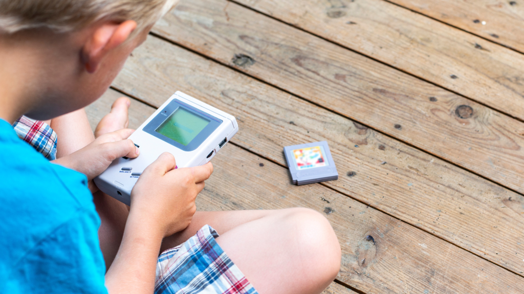 kid playing gameboy on wooden floor outdoors